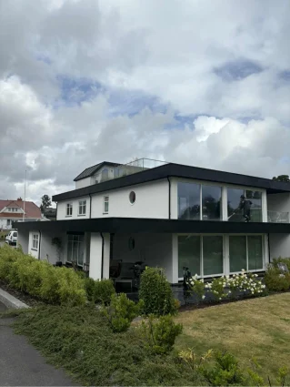 Enebolig med hvit fasade sett fra hagen